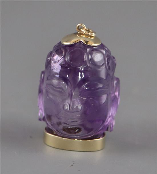 A yellow metal mounted amethyst pendant, carved as the head of Buddha, 36mm.